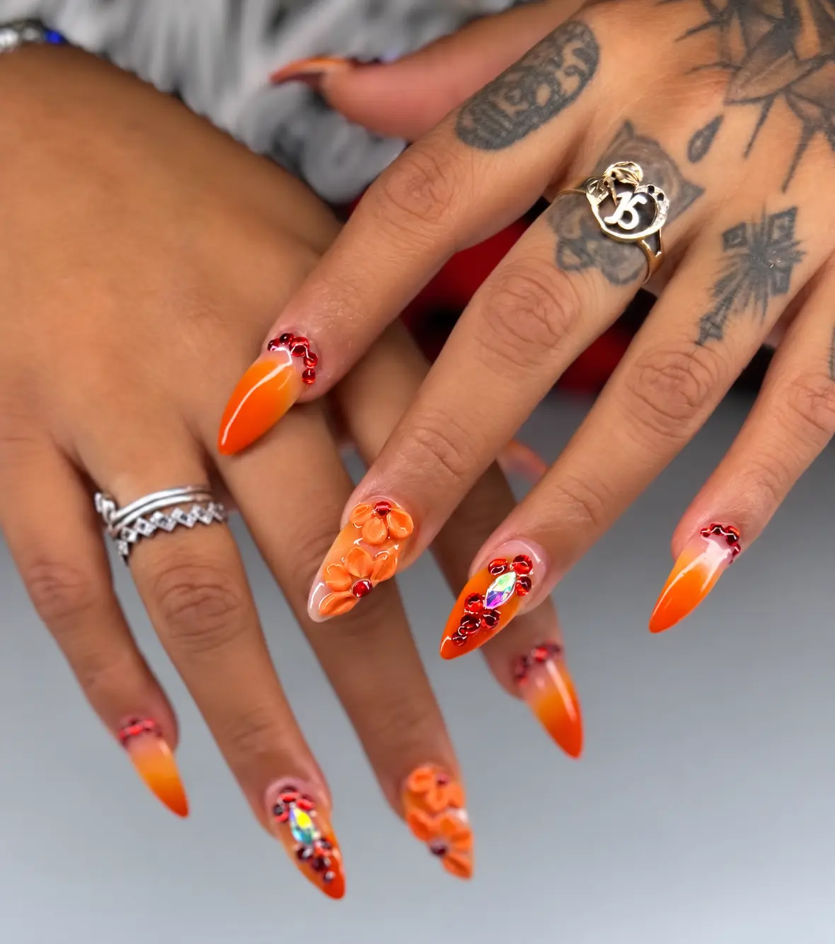 Orange almond nails with orange flowers and red rhinestones