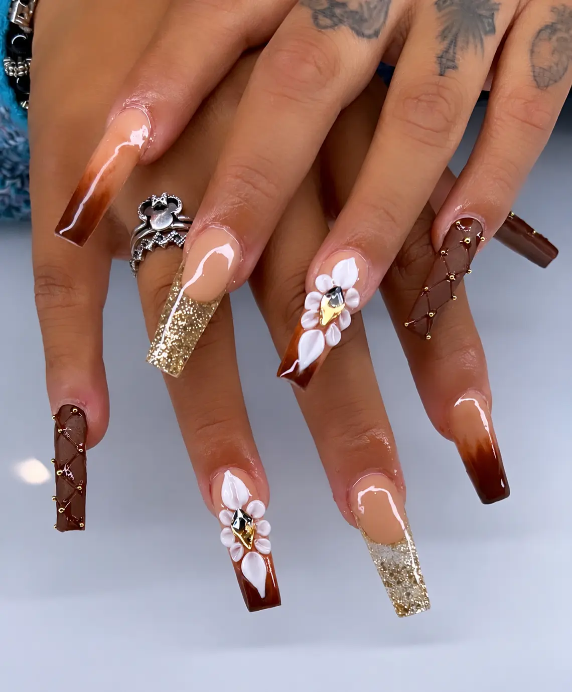 Chocolate square nails with gold glitter, sculpted white flowers and gold studs