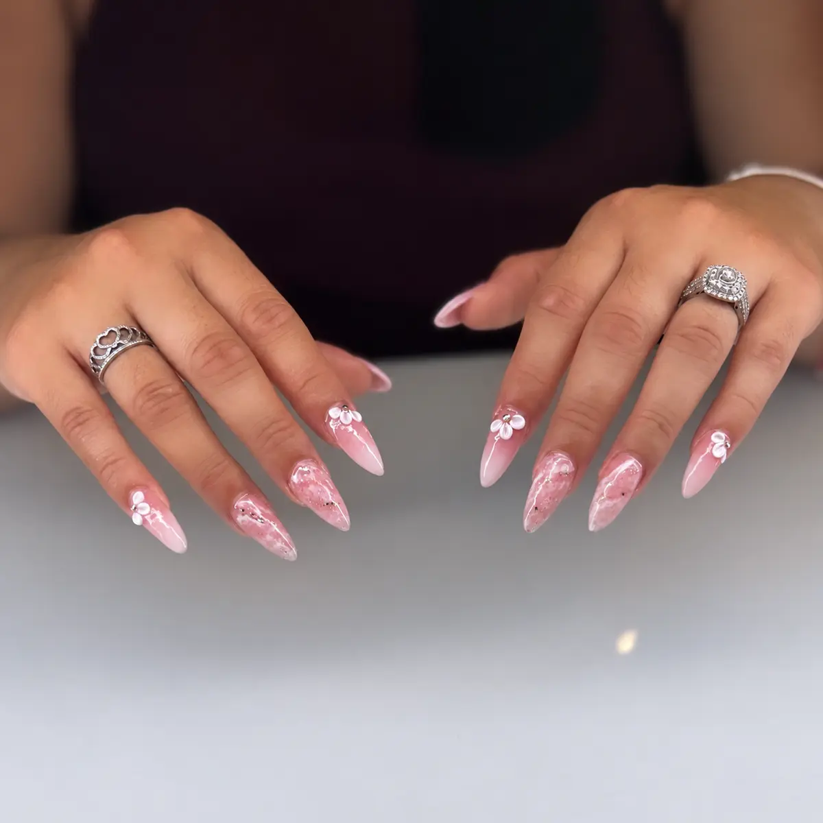 Pink almond nails with marble details, glitter and delicate white flowers